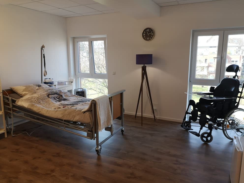 Helles Bewohnerzimmer mit Pflegebett und Rollstuhl in der Intensivpflege-WG